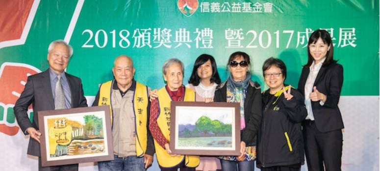 91歲吳健民爺爺(左二)與94歲劉玉芬奶奶(左三)贈送親手繪製的油畫給信義公益基金會，由林信和董事長(左一)及蔡易臻執行長(右一)代表接受