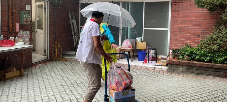 信義房屋新莊公園店在大雨中協助社區運送普渡物資